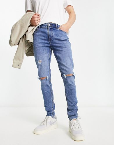 Jeans skinny lavaggio medio con strappi - ASOS DESIGN - Modalova
