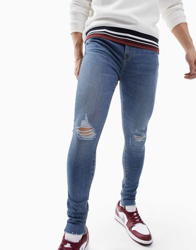 Jeans power stretch lavaggio medio effetto spray con abrasioni - ASOS DESIGN - Modalova